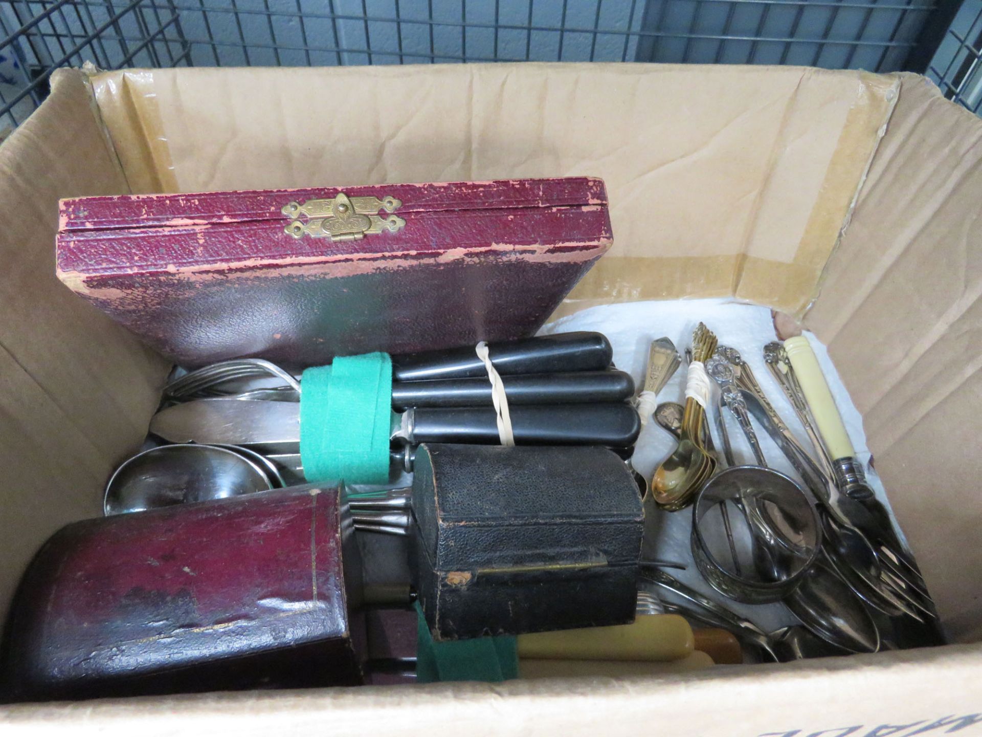 Cage containing loose cutlery plus napkin rings and a cased teaspoon set