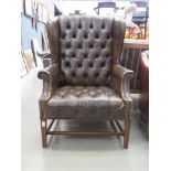 Button-backed wing armchair in brown