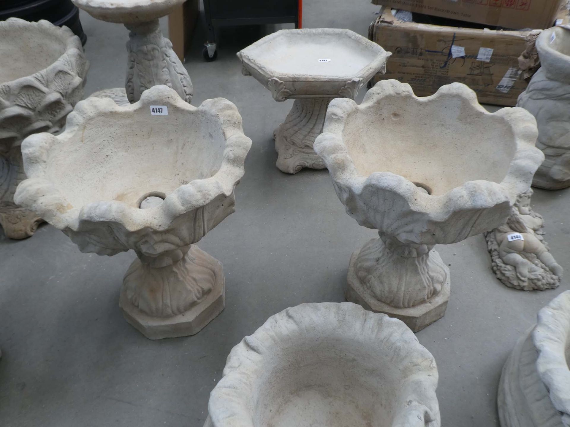 2 floral topped concrete pots on stands
