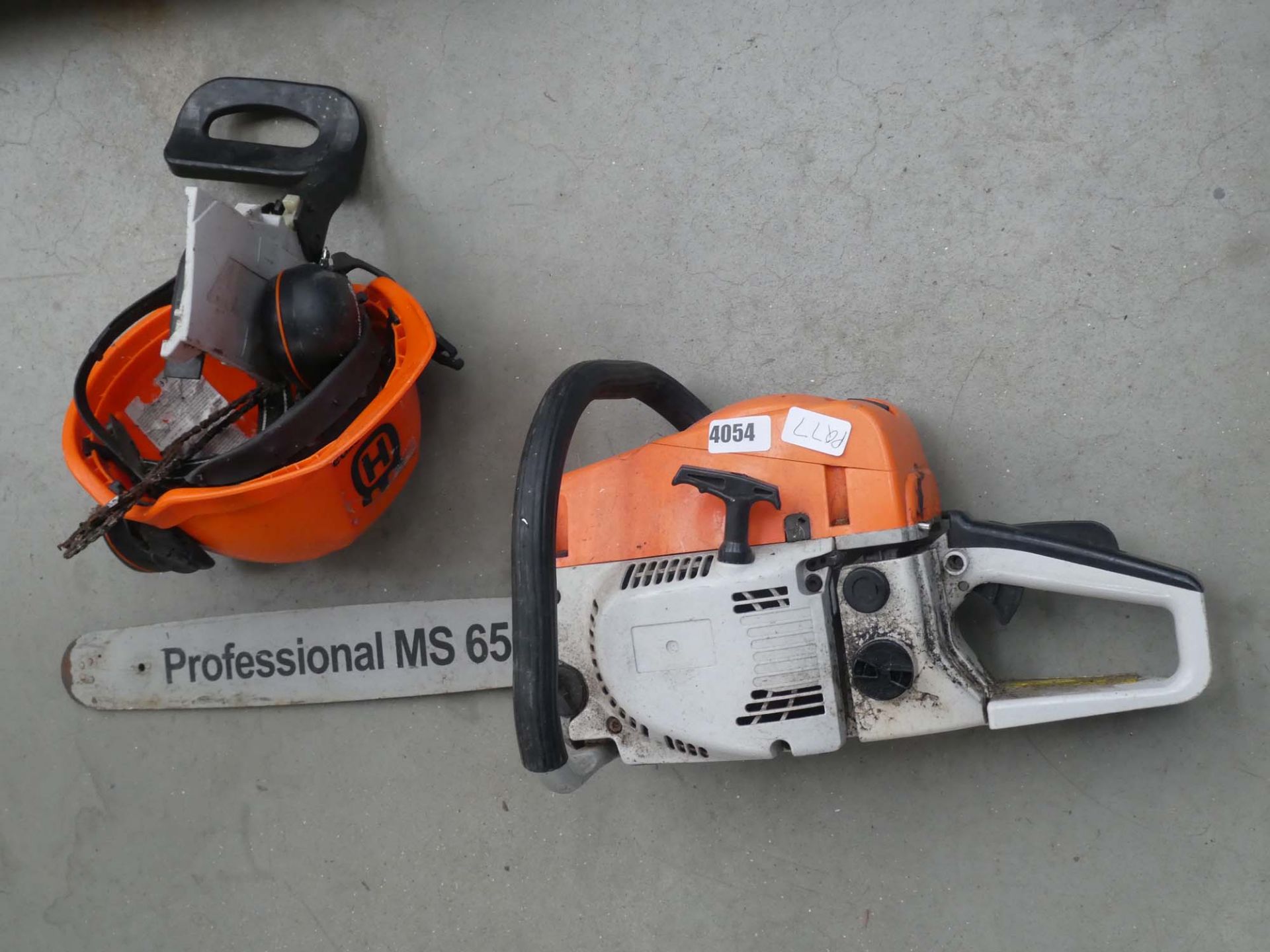 Orange and white petrol powered chainsaw with Husqvarna helmet