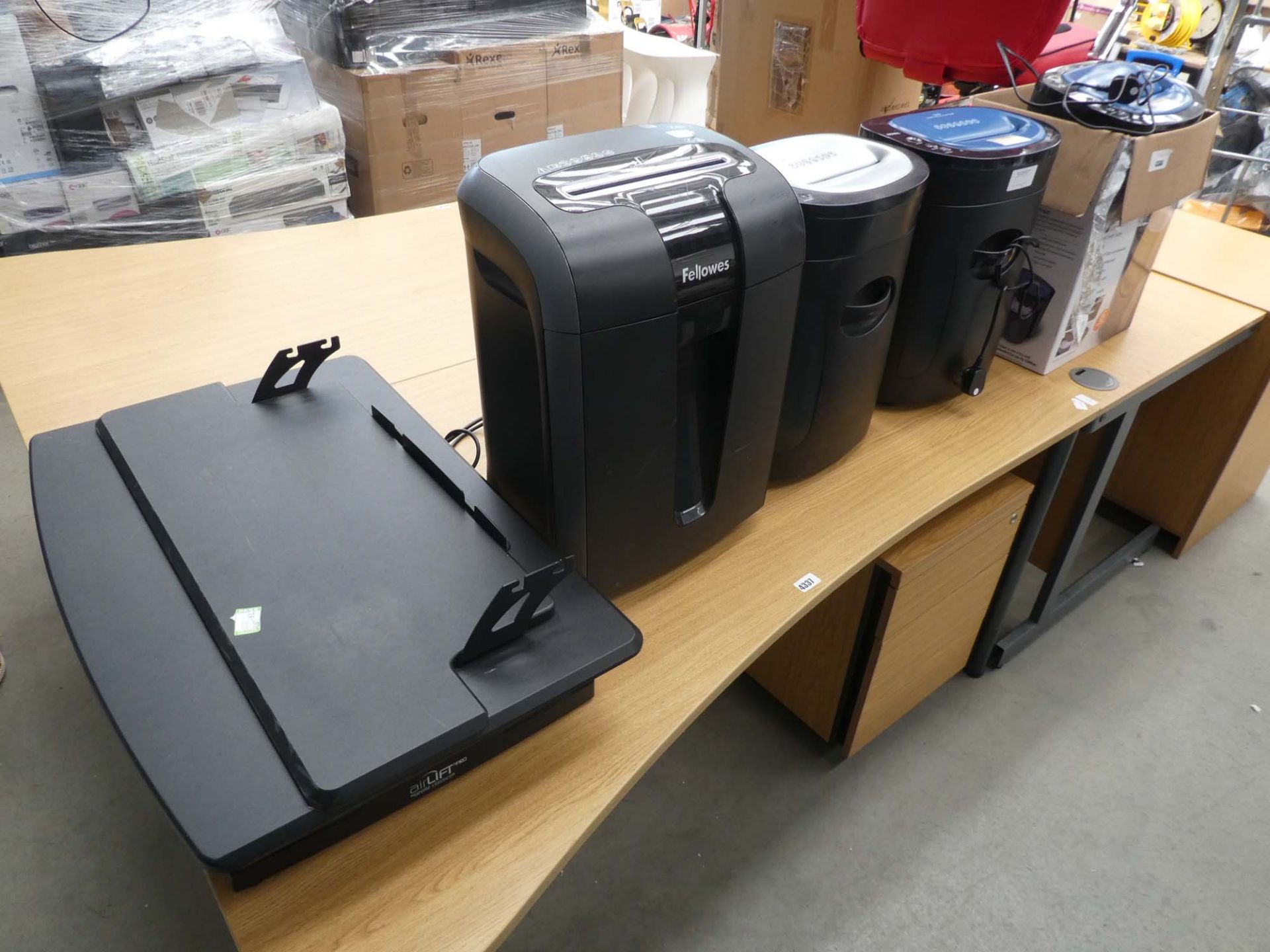 Boxed and 3 unboxed paper shredders and a small desk riser