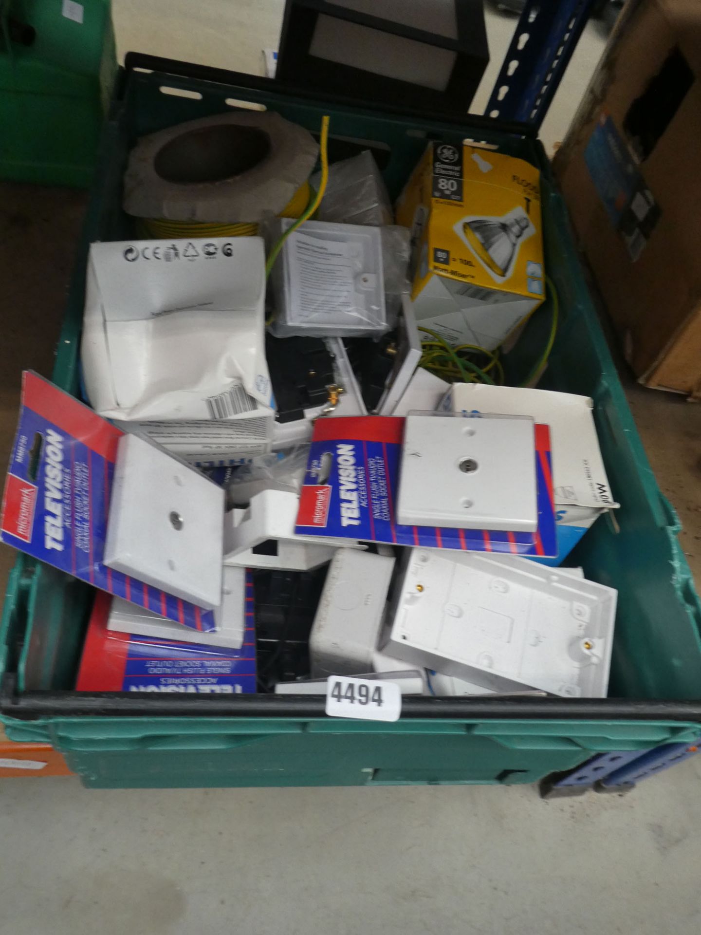 Green plastic crate of assorted electric sockets, lamps and wire