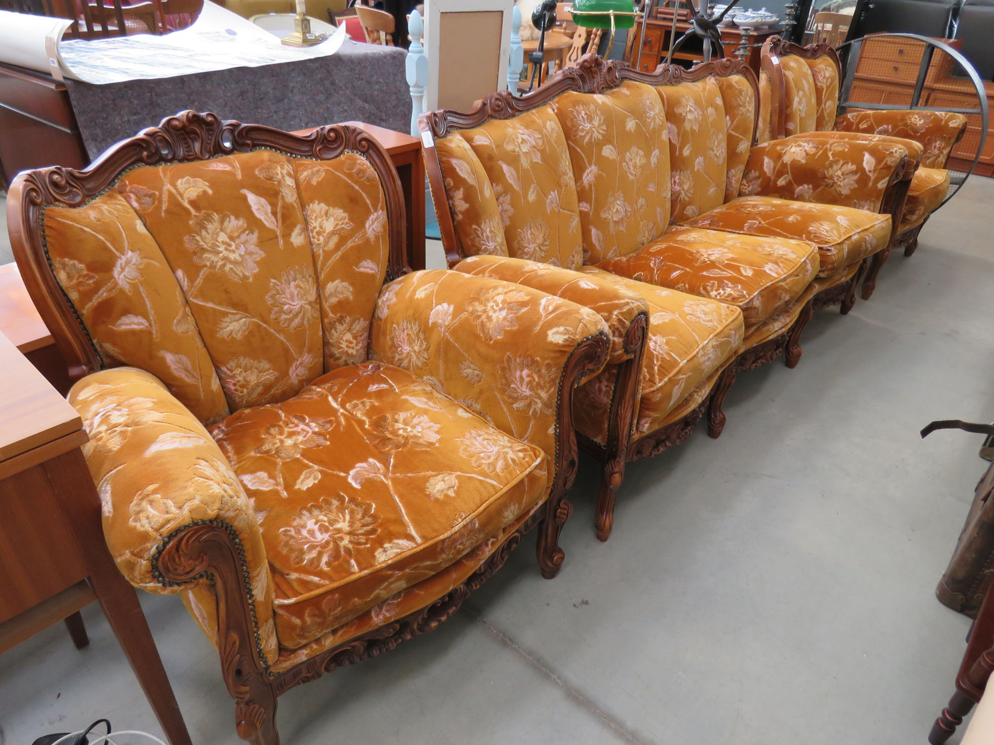 Carved 3 seater sofa with floral patterned brown cushions and pair of matching armchairs