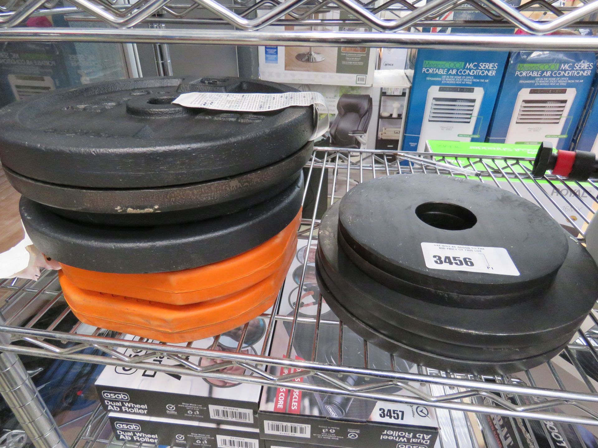 Shelf containing a selection of weight plates a pair of 8kg dumbbells, kettlebells, etc