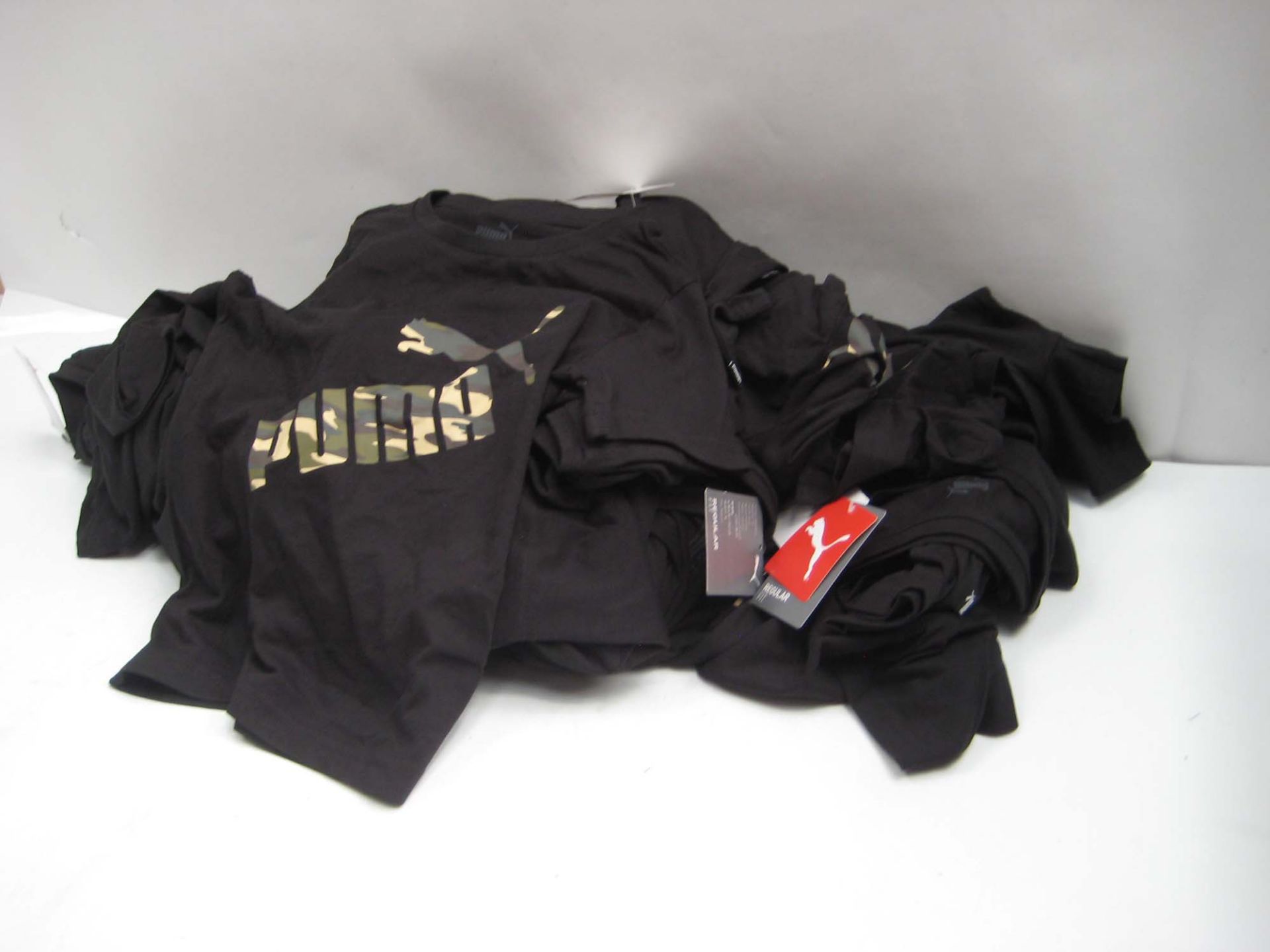 Bag containing childrens Puma t-shirts in white and black with camouflage Puma motif to the front