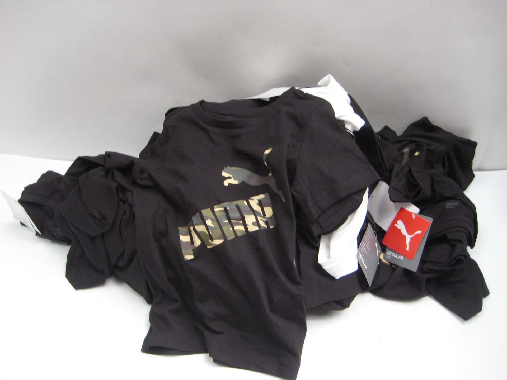 Bag containing childrens Puma t-shirts in white and black with camouflage Puma motif to the front