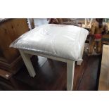 Upholstered footstool with white supports