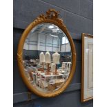 Oval bevelled mirror in decorative gilt frame
