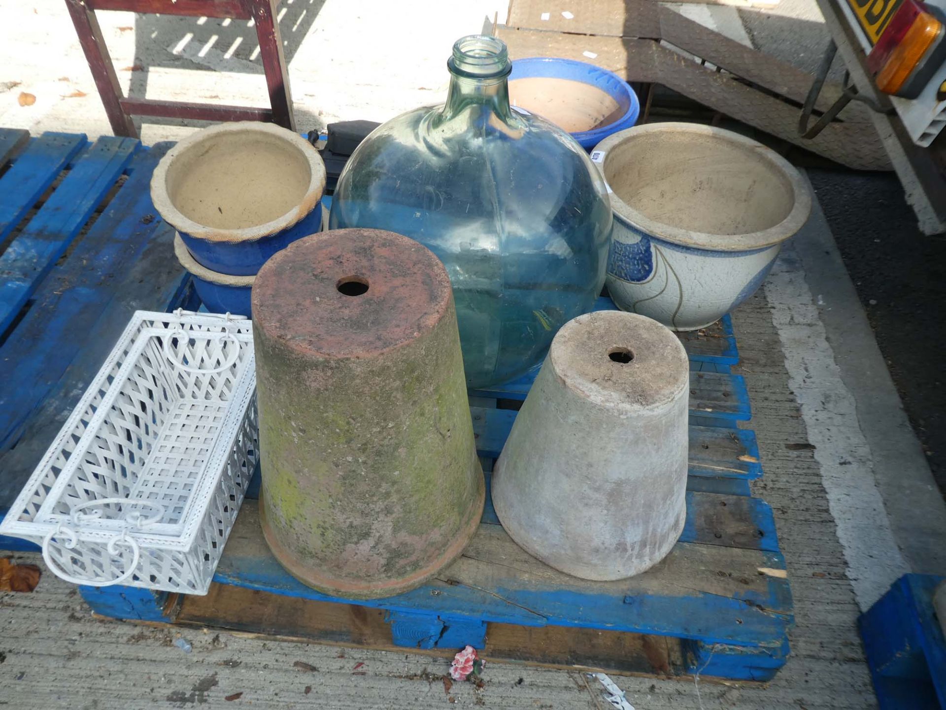 Pallet containing large car buoys, flower pots, and metal fire front