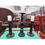 Set of three graduated ebonised candlesticks with candles