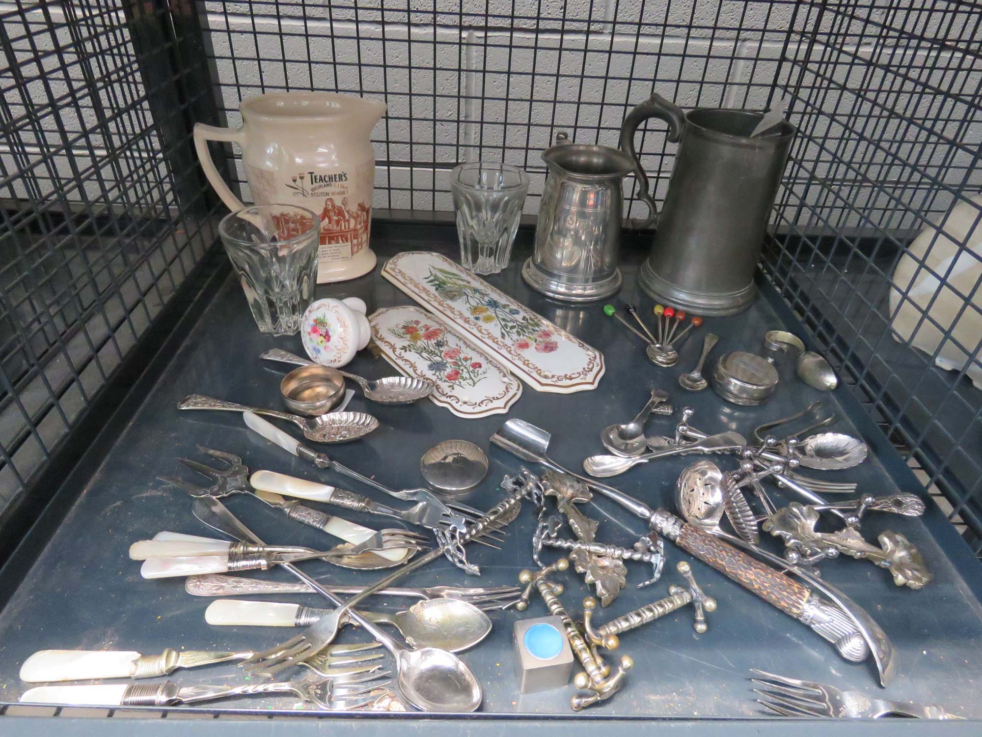 Cage containing loose cutlery, pewter mugs, water jug, door handles and touch plates