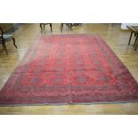 A 20th century woolen rug, the red ground with repeated motifs within matching borders,