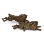 A cold-painted bronze figural group modelled as a pair of leaping hares, presumably Austrian,