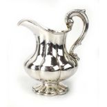 A William IV silver and parcel gilt cream jug with leaf capped c-scroll handle and bulbous body,