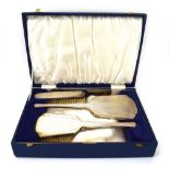 A silver and engine turned four piece dressing table set comprising a hand mirror,