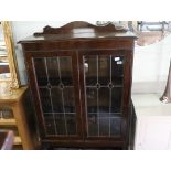 Dark oak double door glazed display cabinet on barley twist plinth with leaded glass doors