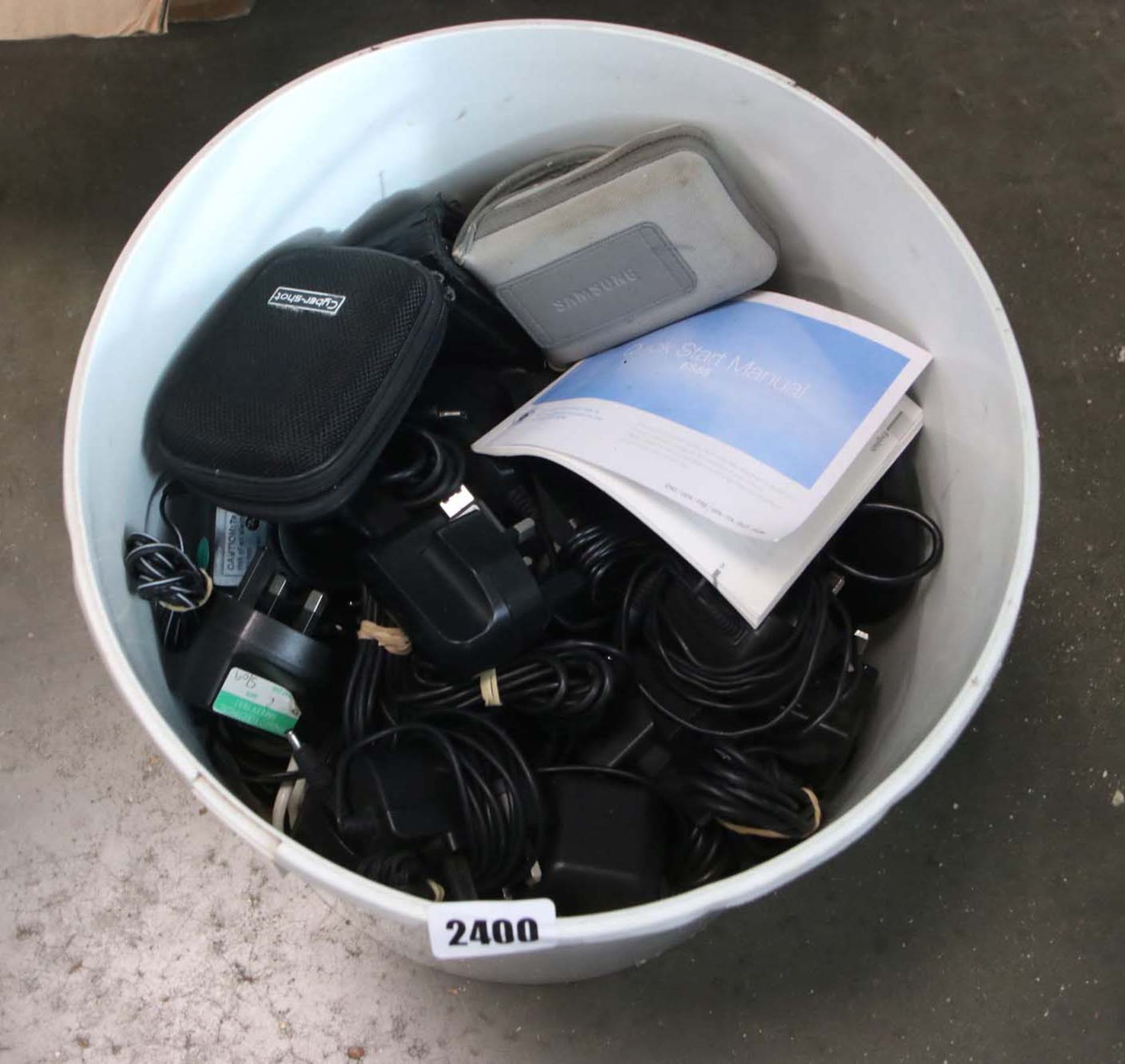 Bucket containing variety of power adaptors and other loose power supplies etc