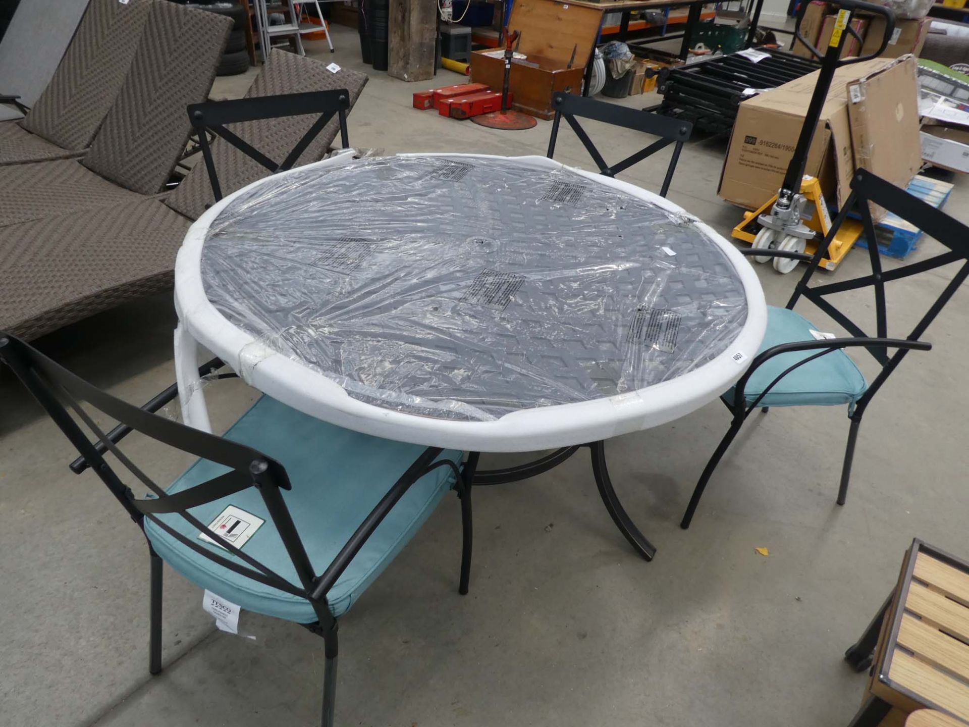 Large circular aluminium garden table on matching supports with 4 matching chairs and blue cushions