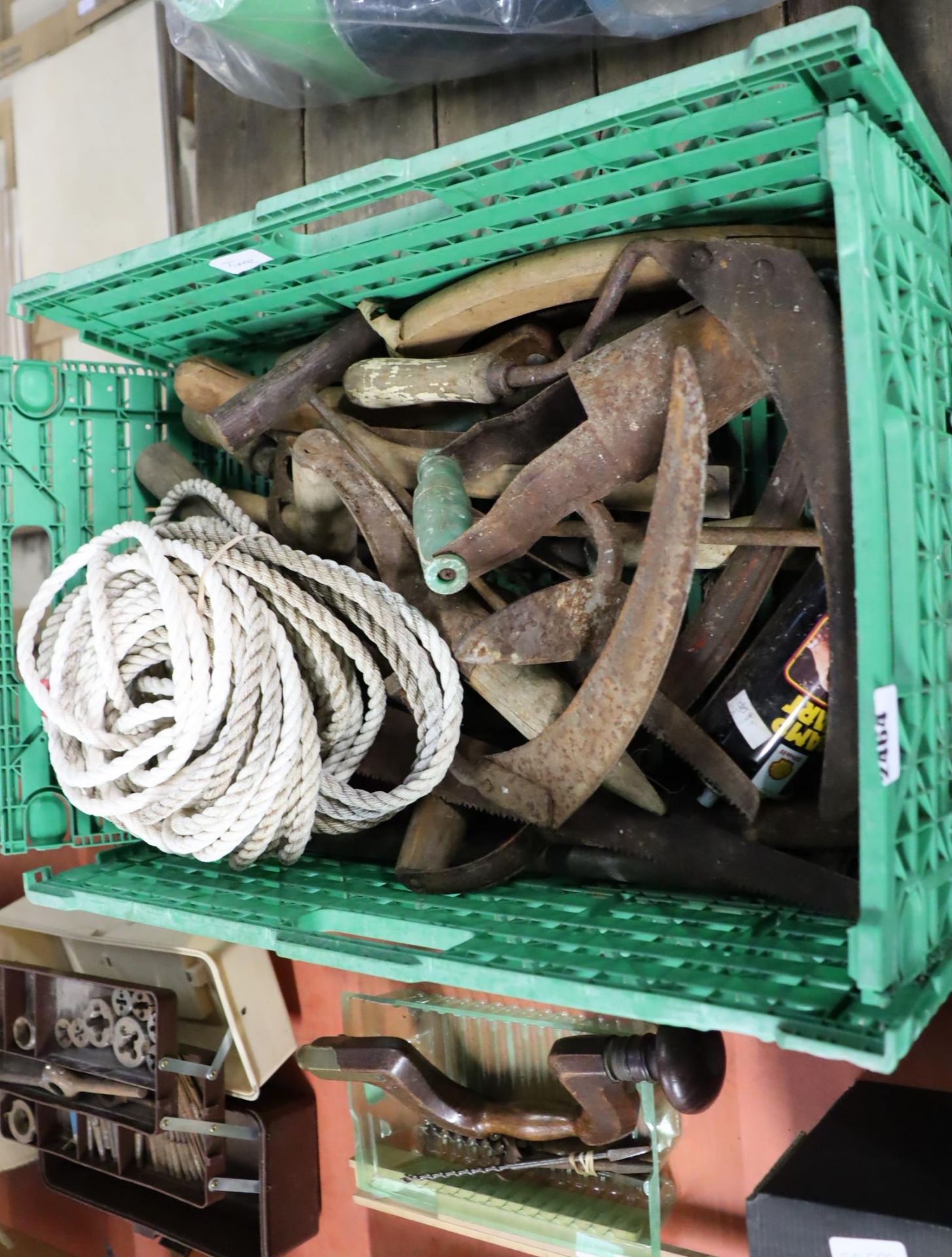 Green crate containing mixed garden hand tools