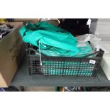 Crate containing green nylon protective PPE suits