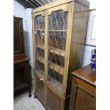 Oak bookcase with leaded glazed doors over cupboard