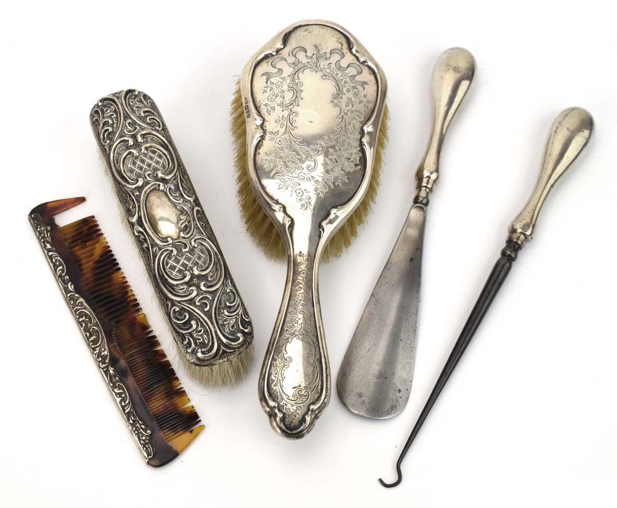 Two early 20th century silver mounted hairbrushes, a comb, a button hook and a shoe horn,