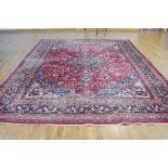 A 20th century Iranian carpet with a red ground, blue floral pattern and matching borders,