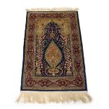 A Turkish silk prayer rug with mihrab, blue ground and red border,