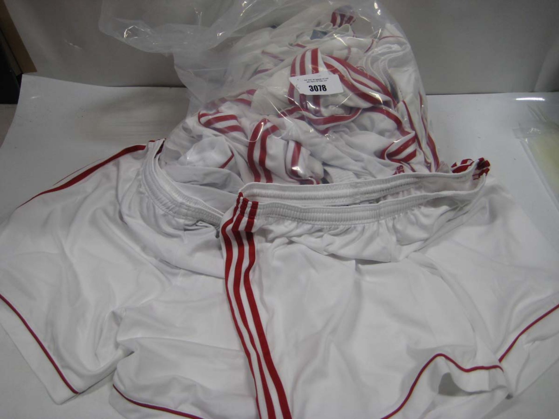 Bag containing 15 Adidas white and red striped sports shorts