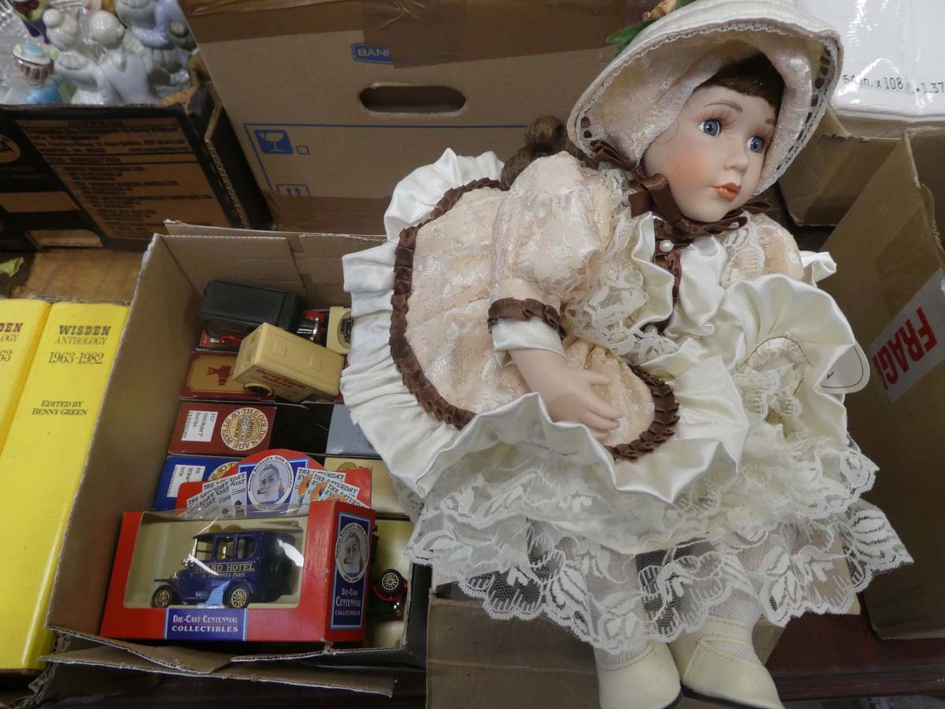 Boxed porcelain doll, plus box containing Dinky cars