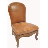 A 19th century oak and leather gout stool in the form of a French fauteuil.