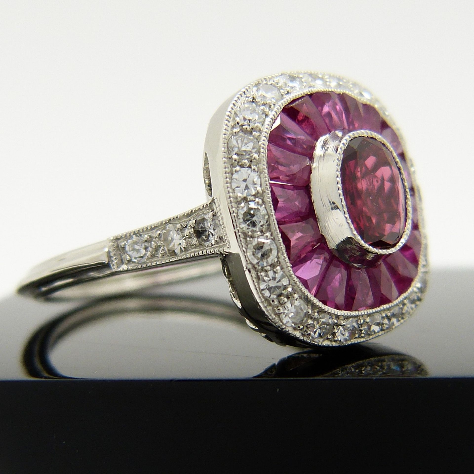 A platinum ring set with central oval-cut and surrounding calibre-cut rubies and round brilliant-cut - Image 2 of 6