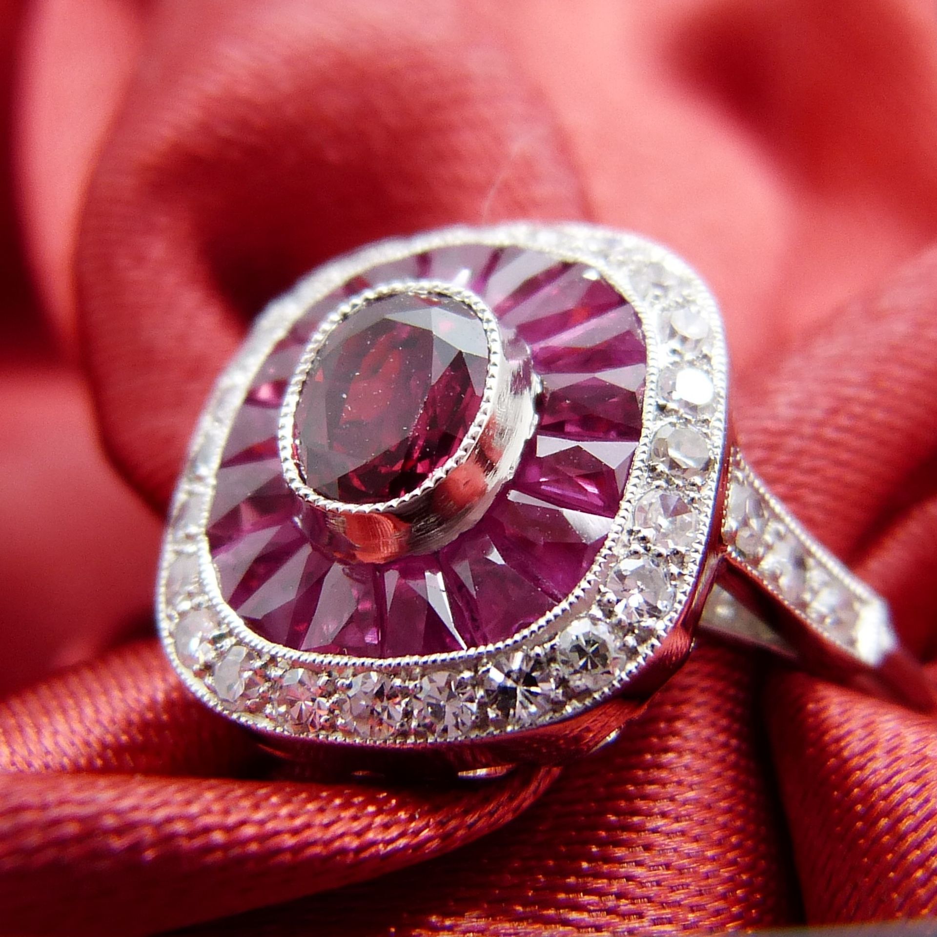 A platinum ring set with central oval-cut and surrounding calibre-cut rubies and round brilliant-cut - Image 4 of 6
