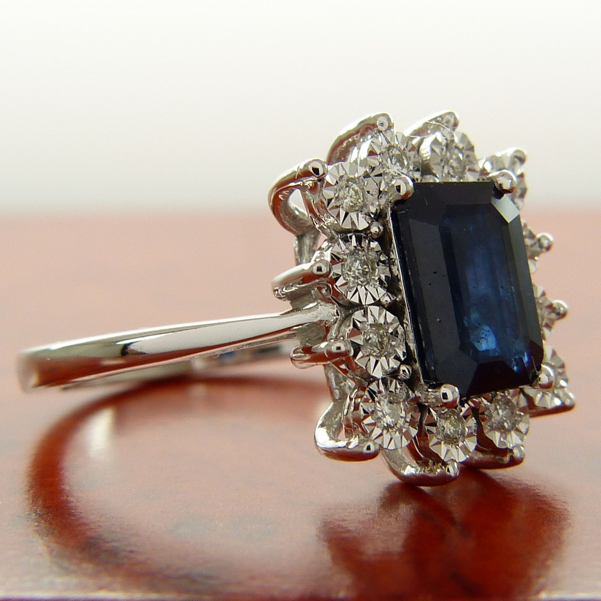 A rectangular treated 0.85 carat sapphire and diamond cluster ring in 9ct white gold