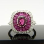 A platinum ring set with central oval-cut and surrounding calibre-cut rubies and round brilliant-cut