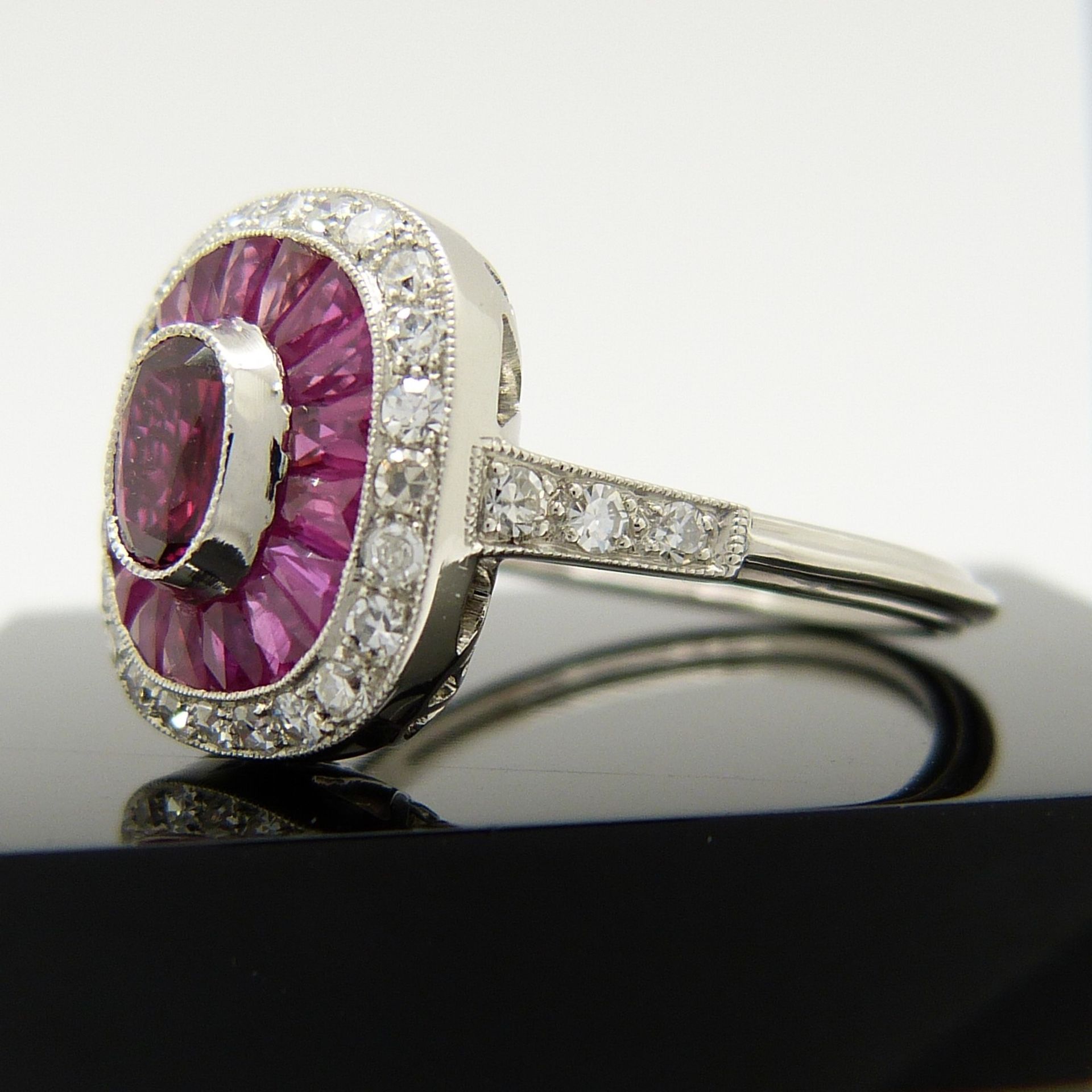 A platinum ring set with central oval-cut and surrounding calibre-cut rubies and round brilliant-cut - Image 6 of 6