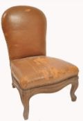 A 19th century oak and leather gout stool in the form of a French fauteuil.