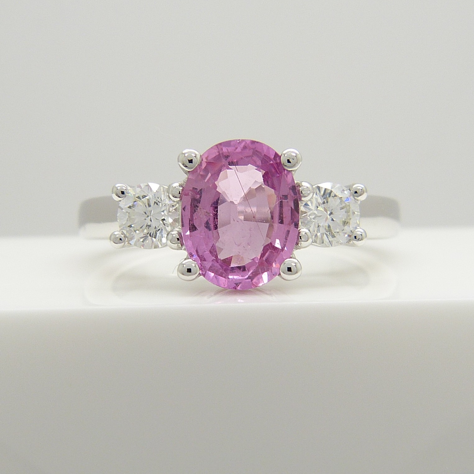 18ct white gold oval-cut pink sapphire and round brilliant-cut diamond dress ring.