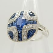 A platinum panel ring set with oval and calibre-cut sapphires and round-cut diamonds.