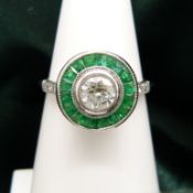 A target-style ring set with round brilliant-cut diamonds and emeralds, in platinum.