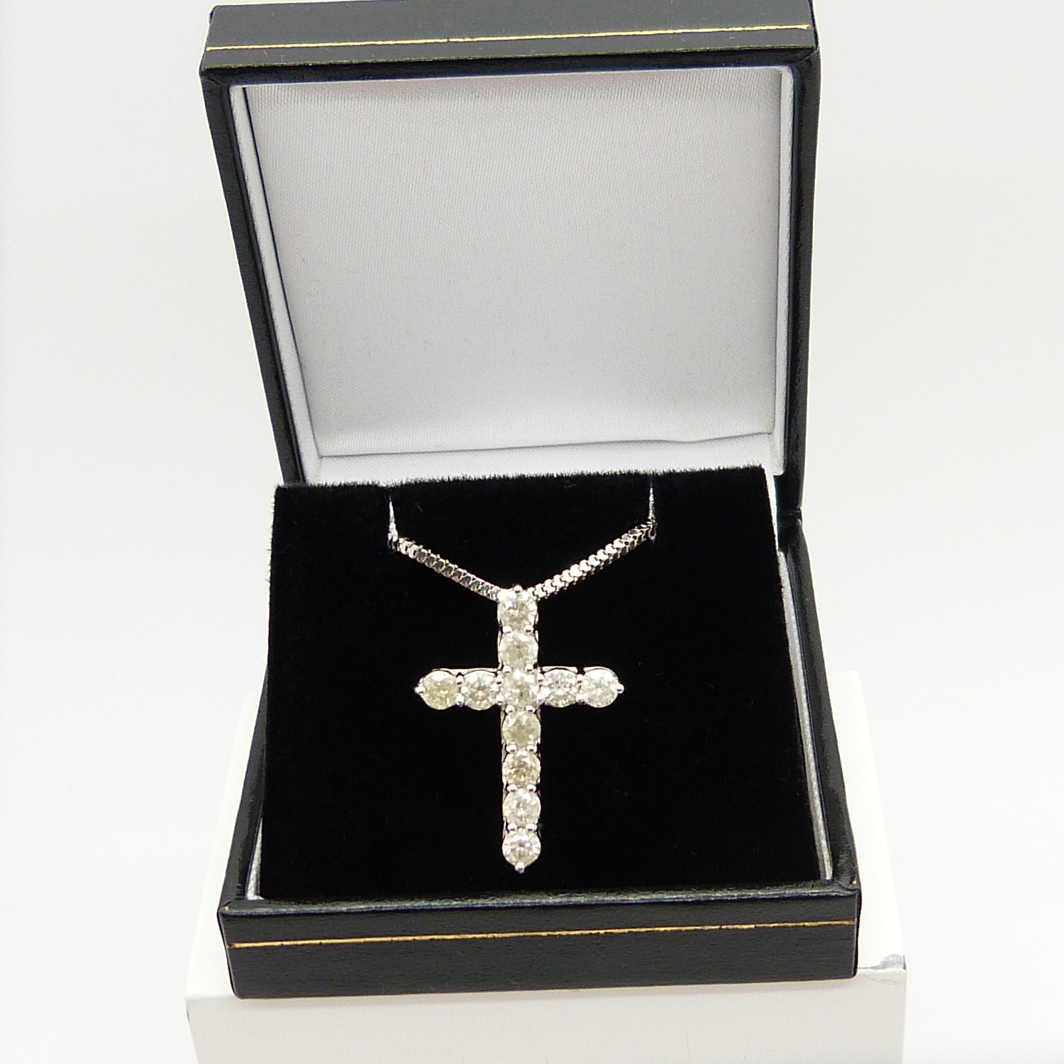 A 14ct white gold diamond cross pendant on a silver snake link chain, boxed