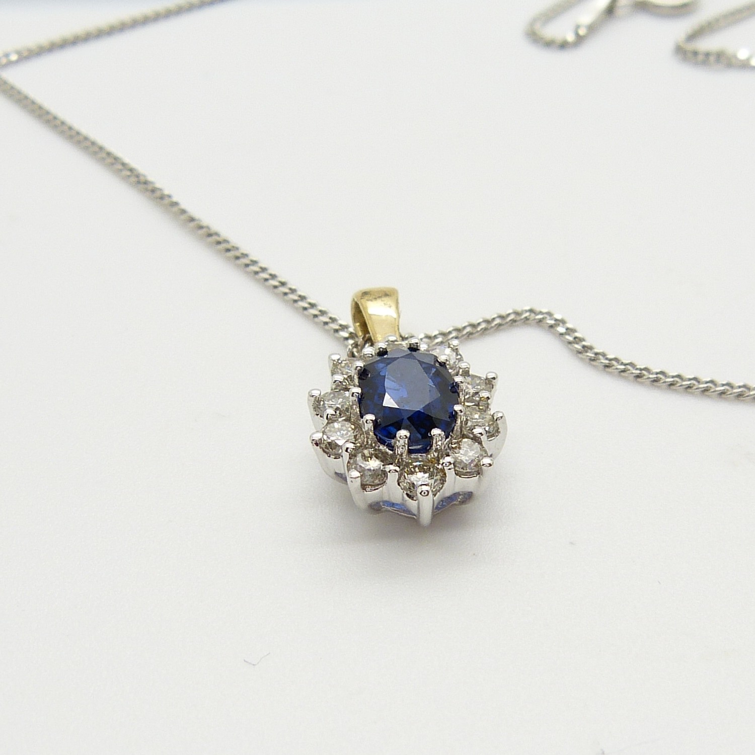 An 18ct yellow and white gold sapphire and diamond cluster pendant on a silver chain, boxed