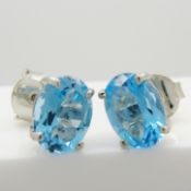 A pair of silver stud earrings set with oval-cut sky blue topaz gemstones