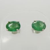 A pair of natural, oval-cut emerald gemstone ear studs in silver