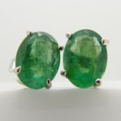 A pair of natural, oval-cut emerald gemstone ear studs in silver