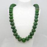 A large and weighty 890.00 ct earth-mined carved graduated emerald bead necklace with patterned cord