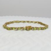 An 18ct yellow gold line bracelet set with peridots and diamonds, boxed