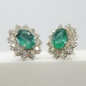 A striking pair of 18ct white gold 3.15 carat emerald and 2.40 carat diamond cluster stud earrings