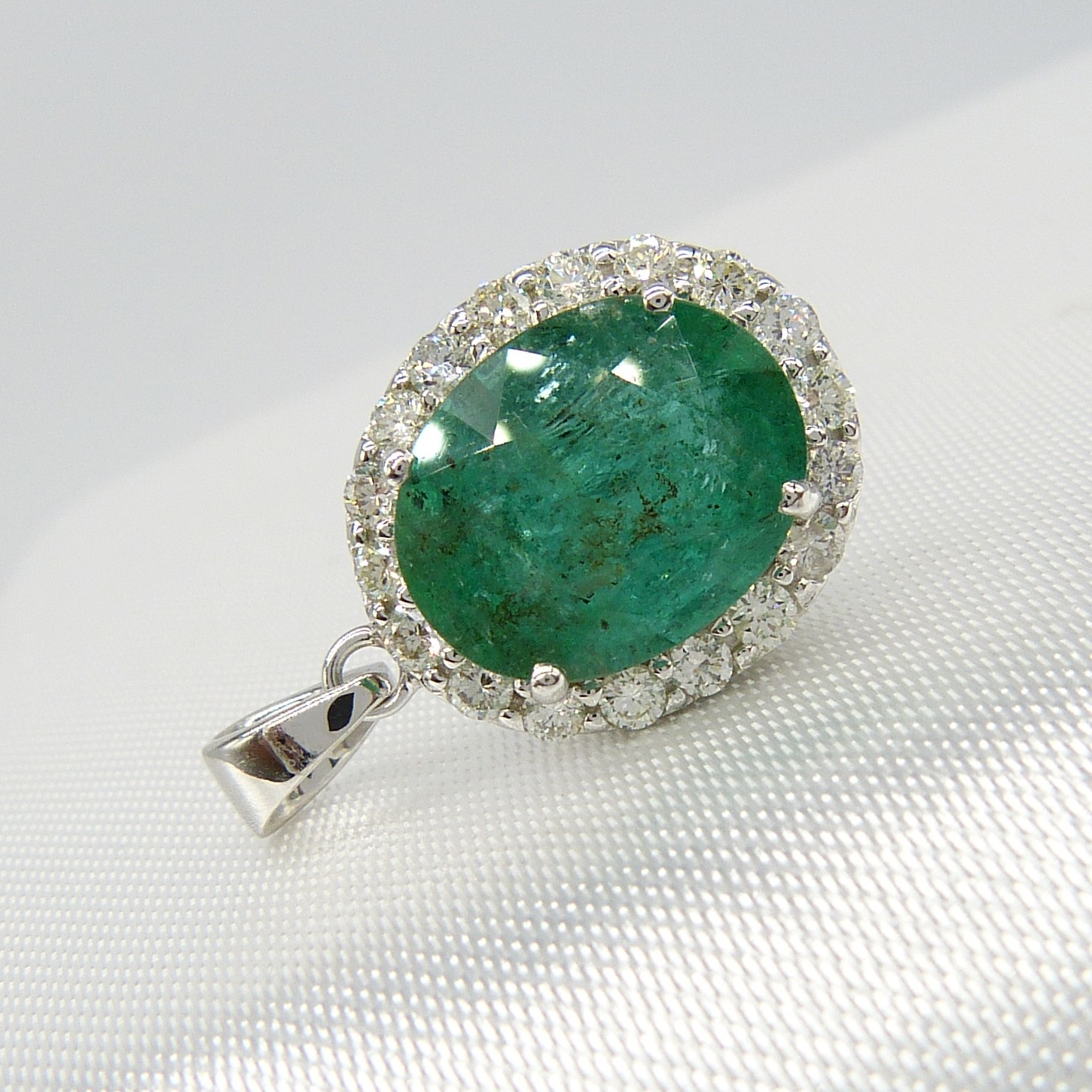 A large emerald and diamond halo pendant in 18ct white gold