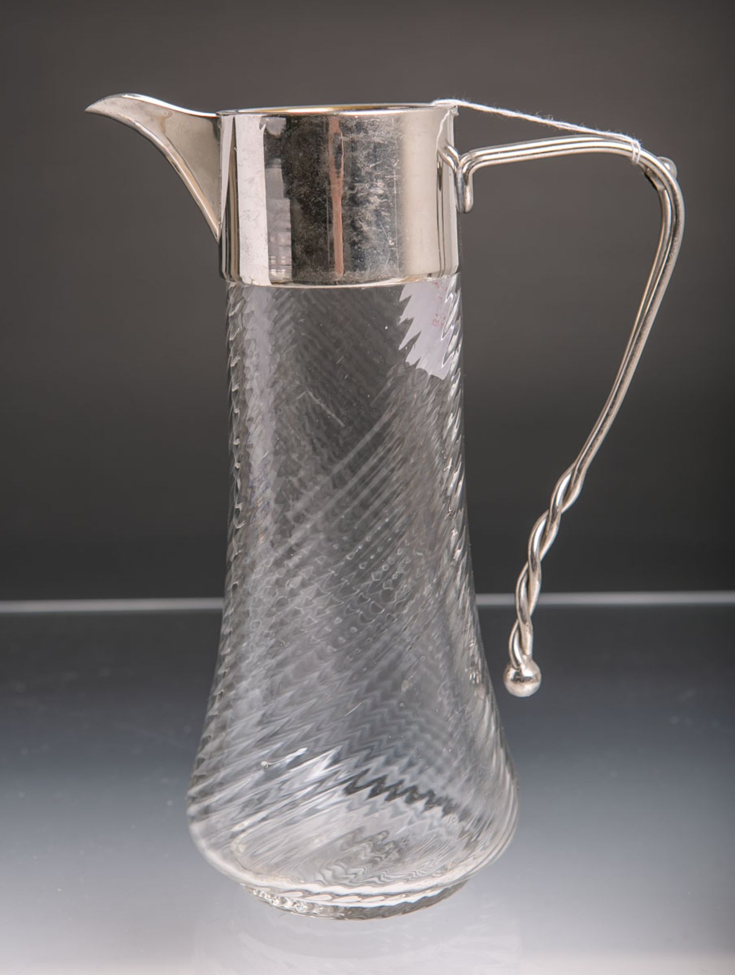 Glasschenkkanne (um 1910/20), klares spiralförmiges Glas m. Metallmontierung, H. ca. 22,5 cm. Deckel